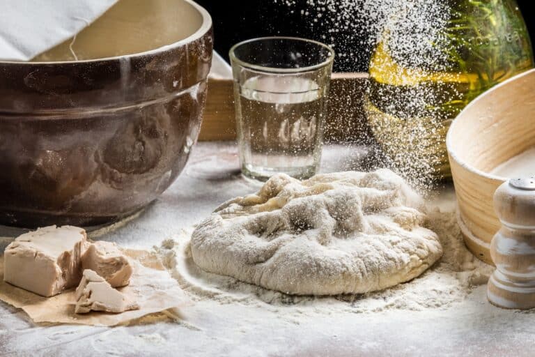 Closeup of sprinkling flour pizza dough