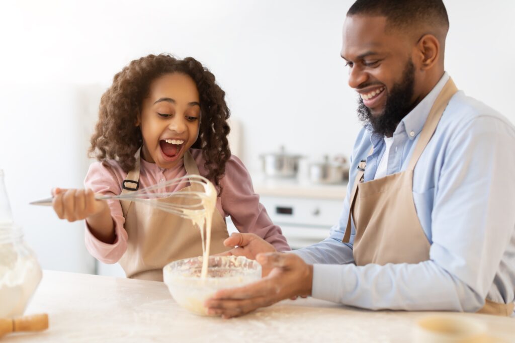 Happy family mixing dough cooking pie together in kitchen